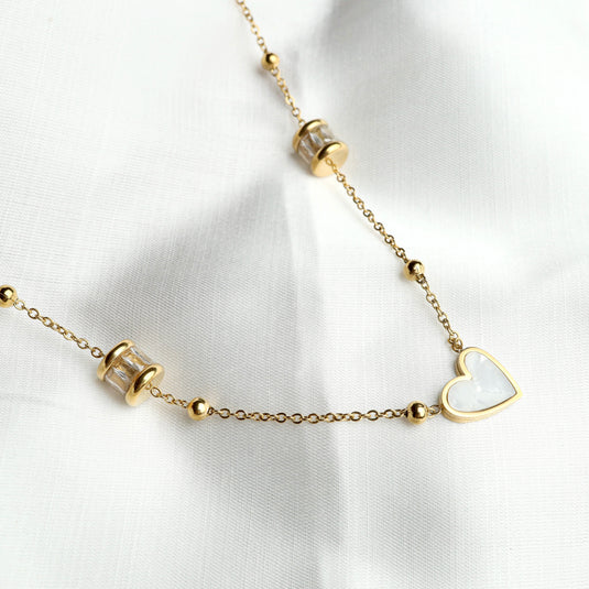 Delicate pearl heart chain necklace with gold links and heart-shaped pendant on white fabric