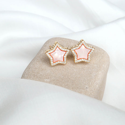 QuinShine rose gold star earrings with pink center and sparkling border on beige stone