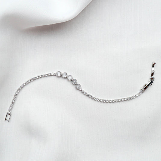 QuinShine bezel set tennis bracelet with sparkling round diamonds on white fabric background