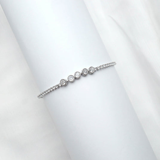 QuinShine bezel set tennis bracelet with round diamonds on a silver chain on white background