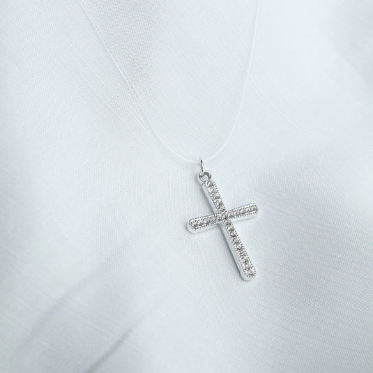 QuinShine silver cross necklace with sparkling stones on a delicate chain against white fabric background