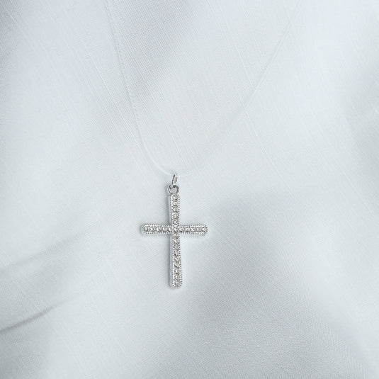 QuinShine silver cross necklace with sparkling stones on delicate chain against white fabric background
