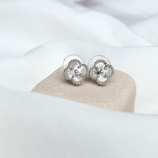 QuinShine silver four leaf clover earrings with intricate detailing on a beige stone