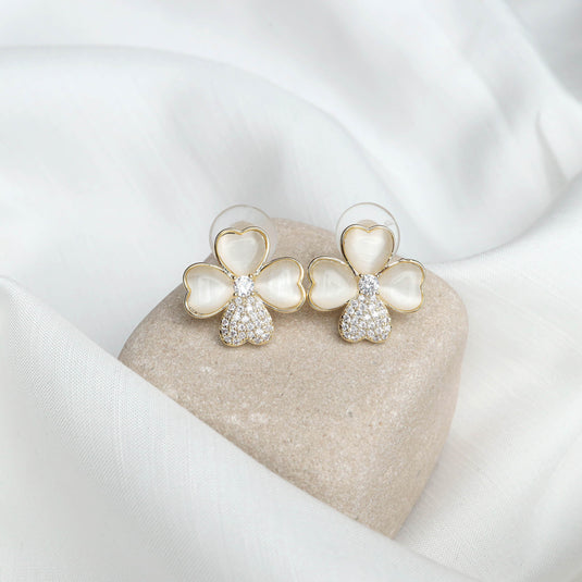 QuinShine stylish floral gold earrings with heart-shaped petals and sparkling accents on a soft fabric background