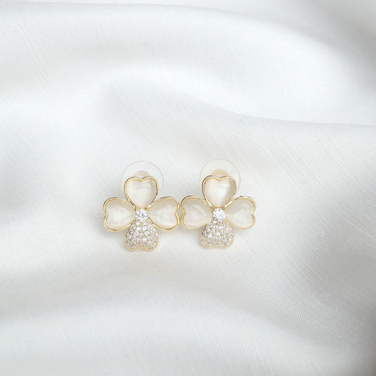 QuinShine stylish floral gold earrings with heart-shaped petals and sparkling accents on white fabric