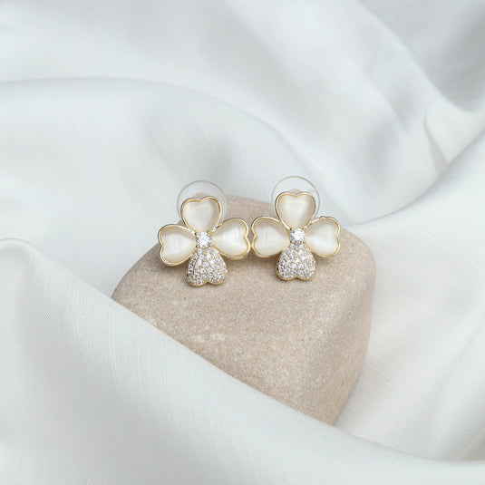 QuinShine stylish floral gold earrings with heart-shaped petals and crystal accents on soft fabric