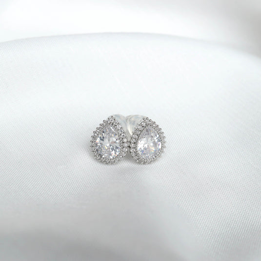 QuinShine tear drop silver earrings with clear gemstones and intricate detailing on white fabric