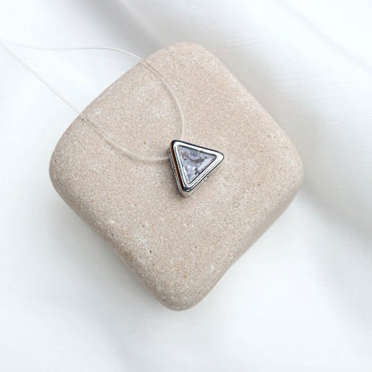 QuinShine transparent chain necklace with triangular silver pendant and clear gemstone on beige stone