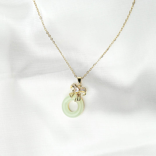 QuinShine unique gemstone jewelry featuring a green circular pendant with a gold bow on a delicate gold chain