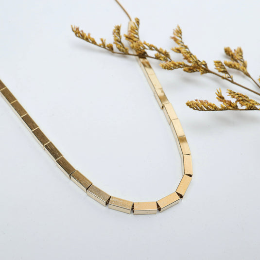 Gold-tone unique square bead jewelry necklace displayed with dried plant decoration