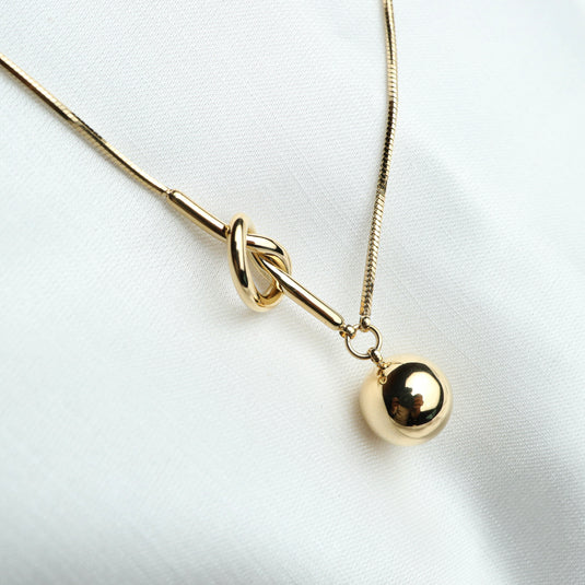 Elegant gold knot lariat necklace with a smooth round pendant on a fine chain