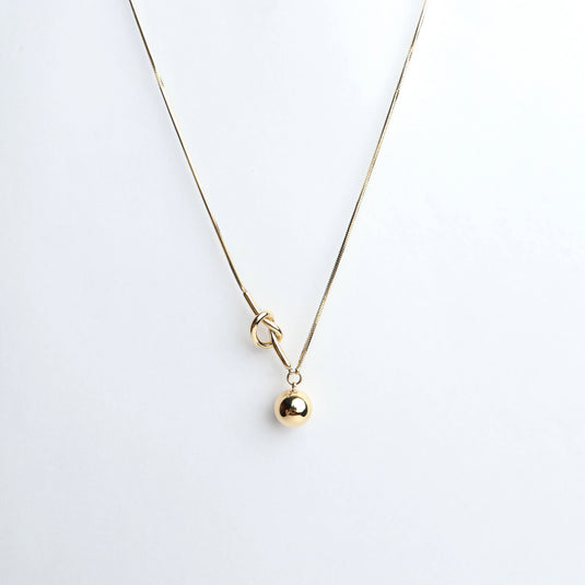 Elegant gold knot lariat necklace with a delicate chain and polished round pendant