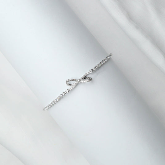 Minimalist Infinite Bow bracelet with delicate silver bow design and sparkling chain on white background
