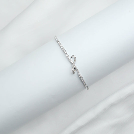 Minimalist Infinite Bow bracelet with delicate silver chain and sparkling stones on white background