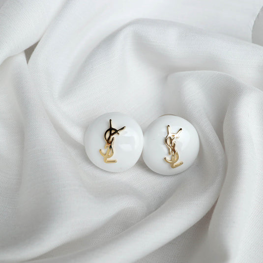 QuinShine white domed stud earrings with gold logo on white fabric background