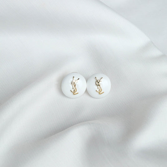 QuinShine white domed stud earrings with gold logo details on white fabric background